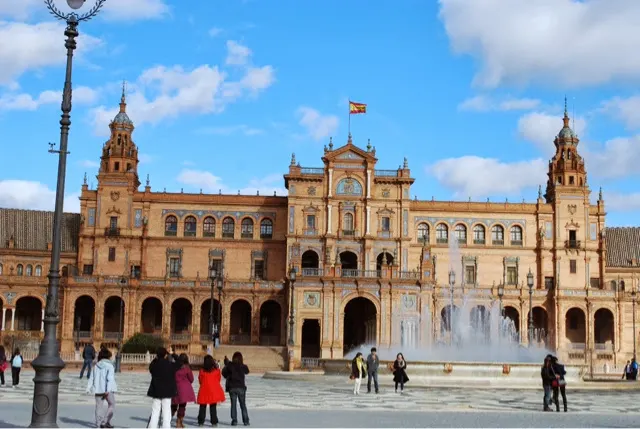 The Plaza de Espana. The camera cannot capture it all. It would take two more camera shots to capture it all. The building is oval shaped with a mote in front of ot. You can rent boats to paddle in the mote. The plaza is huge.