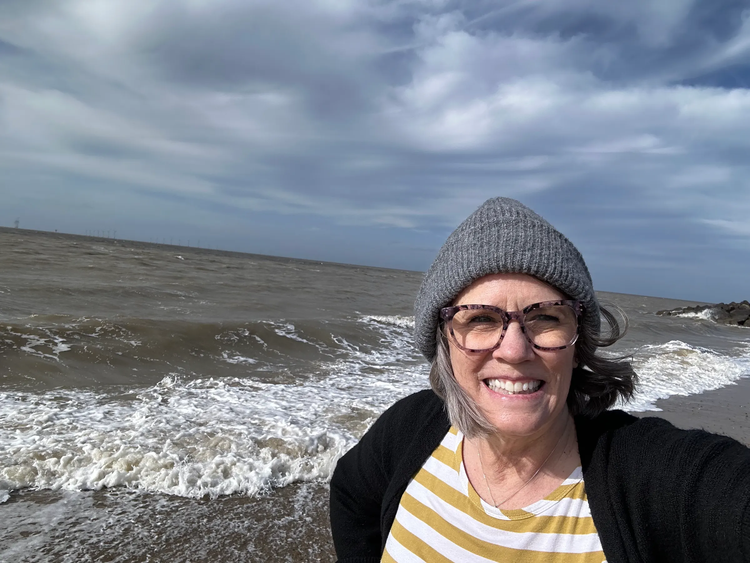 Denise enjoying the beach….with a sock hat on in April.