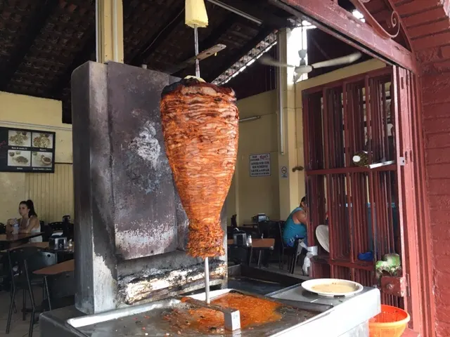 The stacked meat on the skewer. They refer to this as 'Pastor'....and it is the BEST! You can see the pineapple on top that they add to the taco after they carve the meat off.