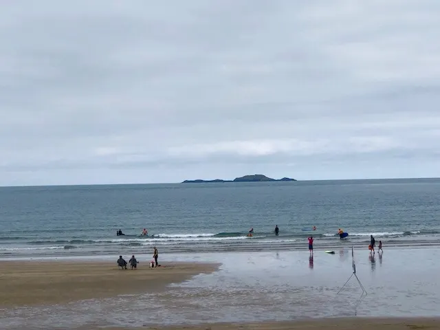 A nice beach\cove where people were setting up for the day. People were already surfing...